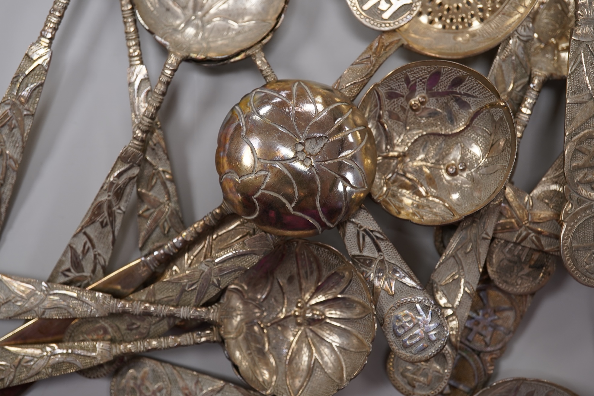 A set of twelve early 20th century Chinese Export white metal small spoons, maker LS, decorated with foliage and character mark, 10cm, a set of ten similar larger spoons, same maker, 12.3cm and another set a six similar